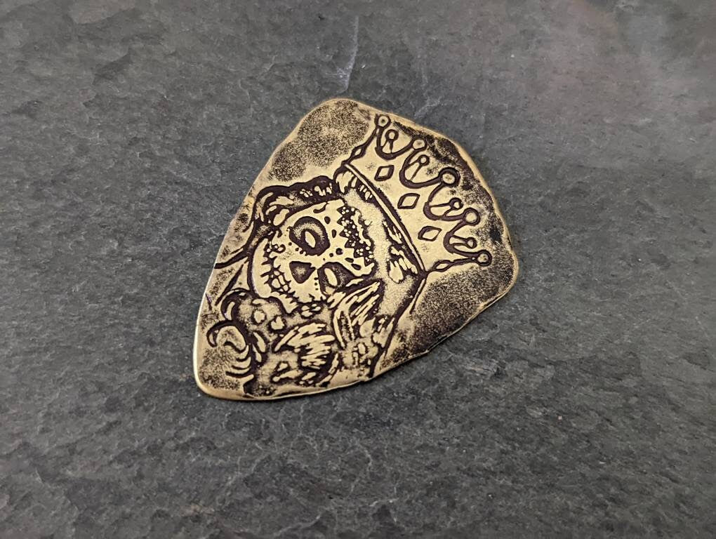 Bronze shield shaped guitar pick with Day of the Dead Theme