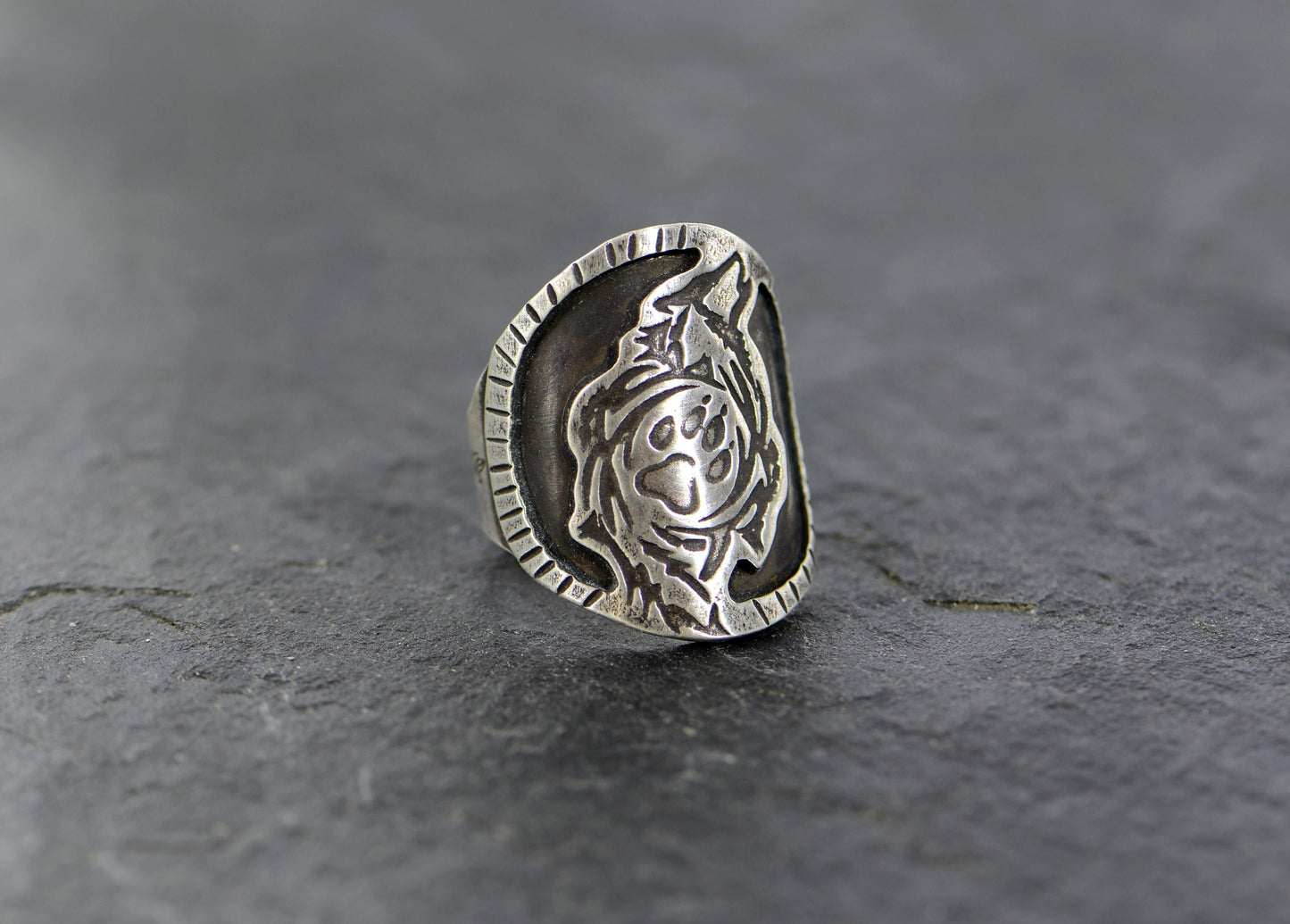 Saddle ring with howling wolf and paw design  in sterling silver