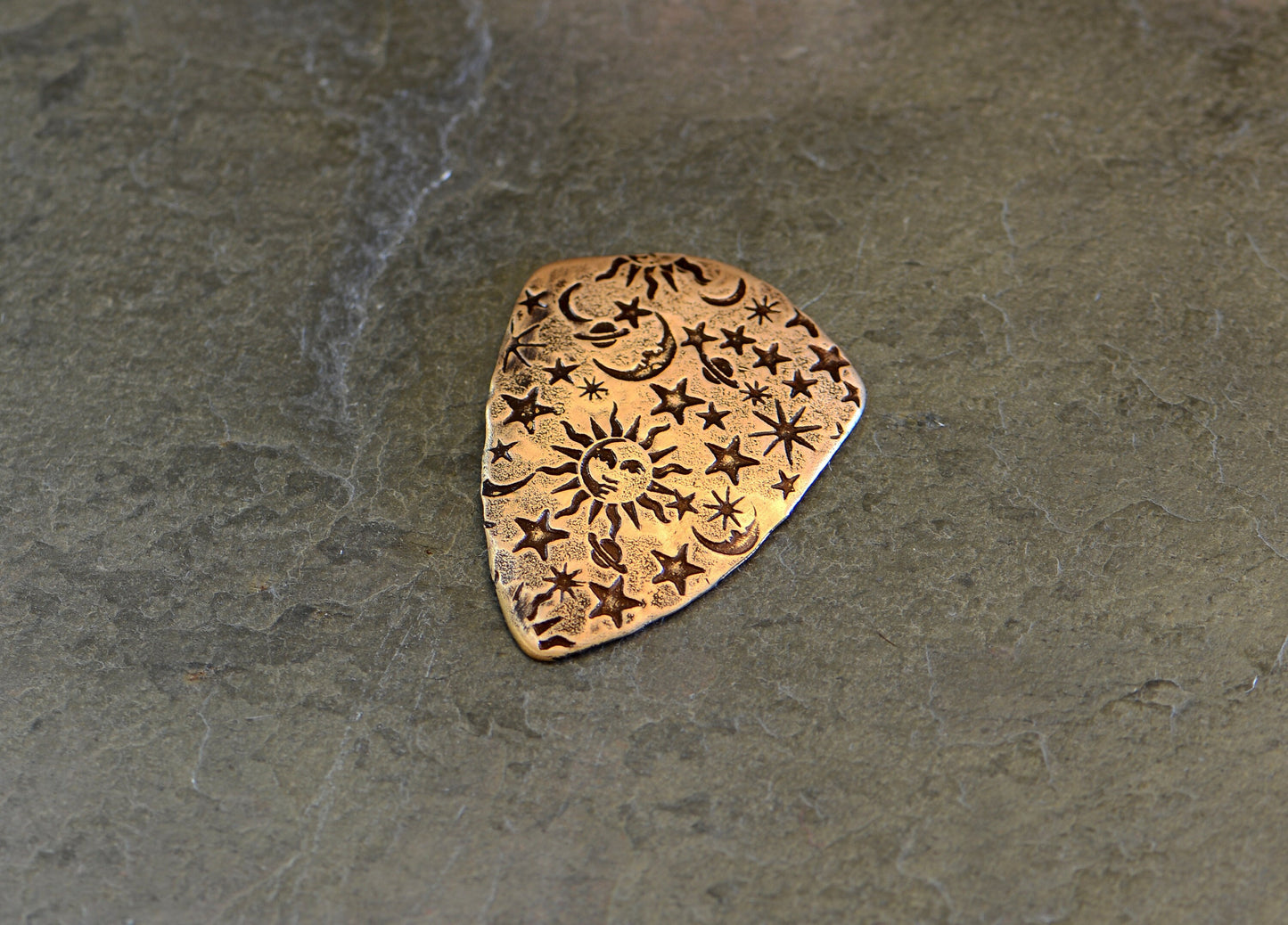 Bronze shield shape guitar pick with sun moon and stars