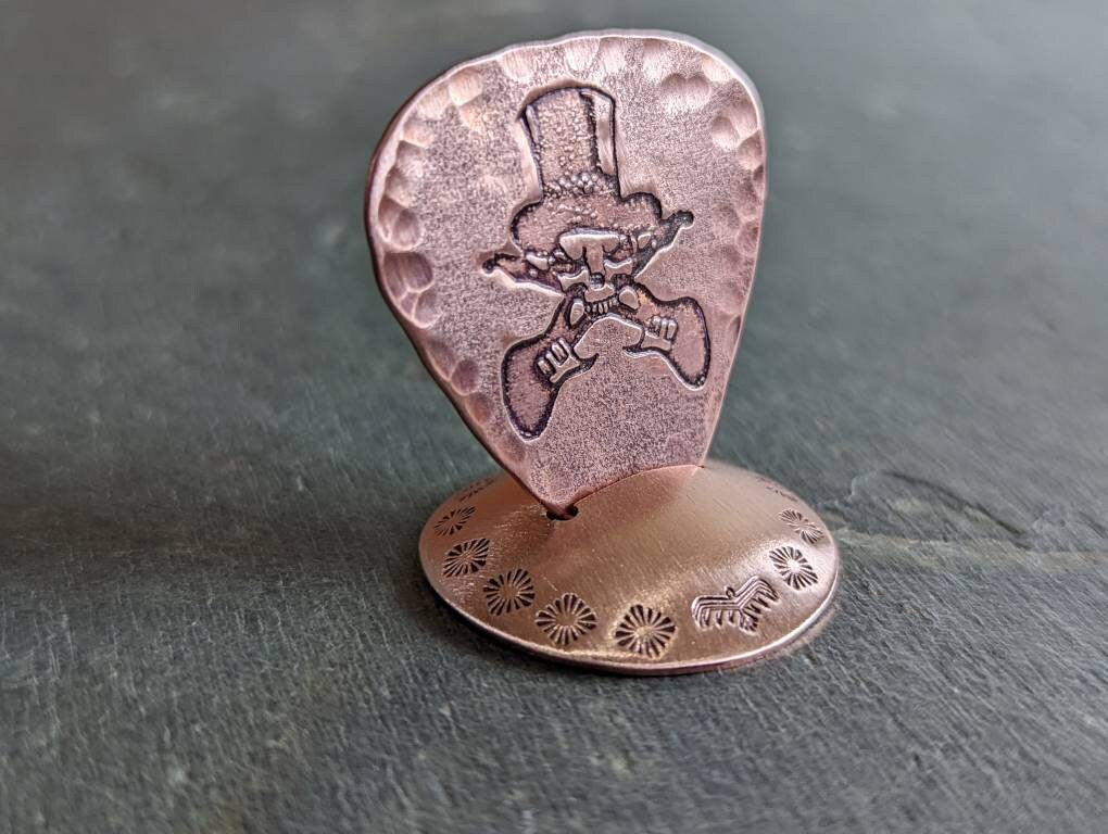 Copper guitar pick with skull and guitars theme
