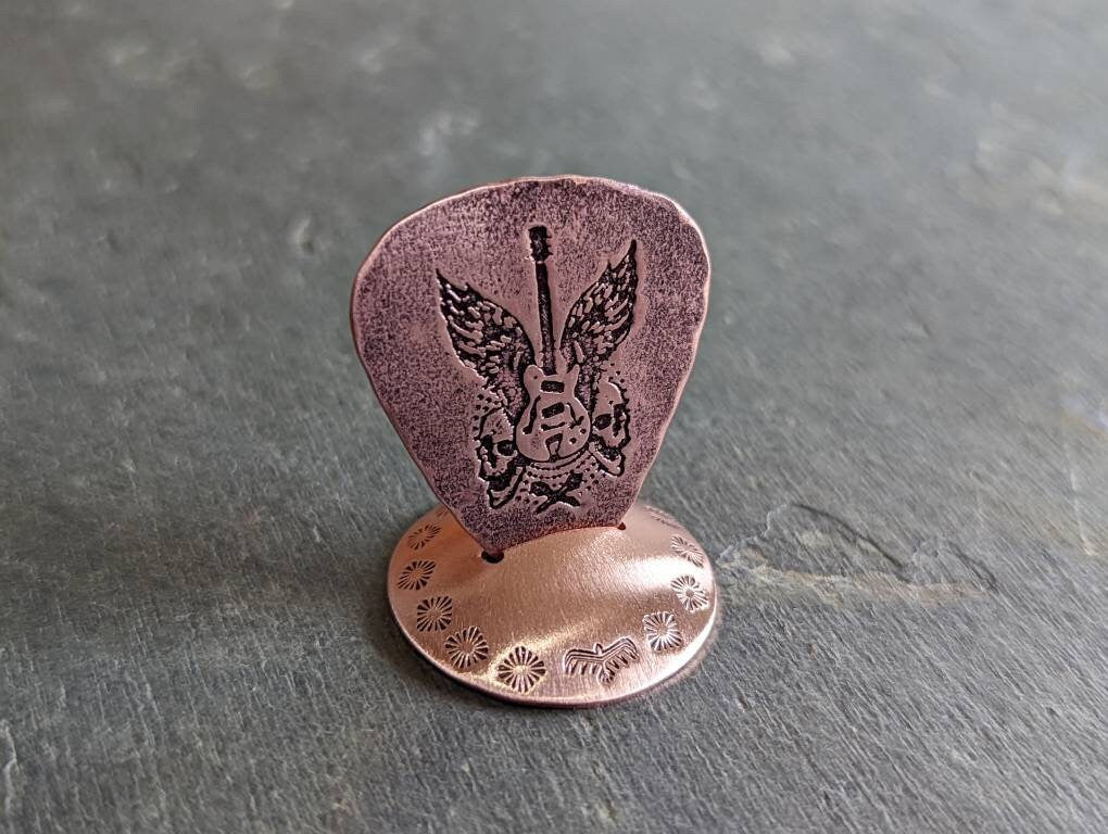 Playable guitar pick with winged guitar and guitar pick stand all in copper