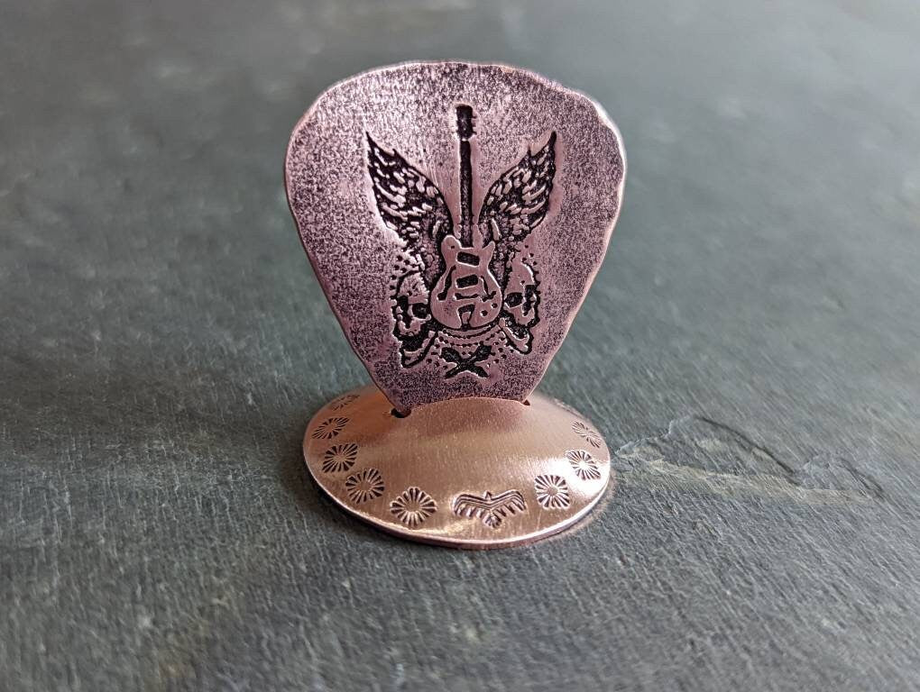 Playable guitar pick with winged guitar and guitar pick stand all in copper