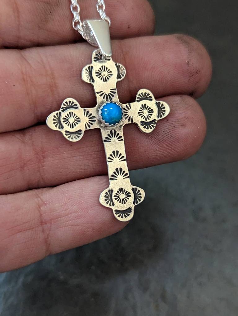 Sterling silver cross with a hand stamped pattern and a 5 mm Kingman turquoise