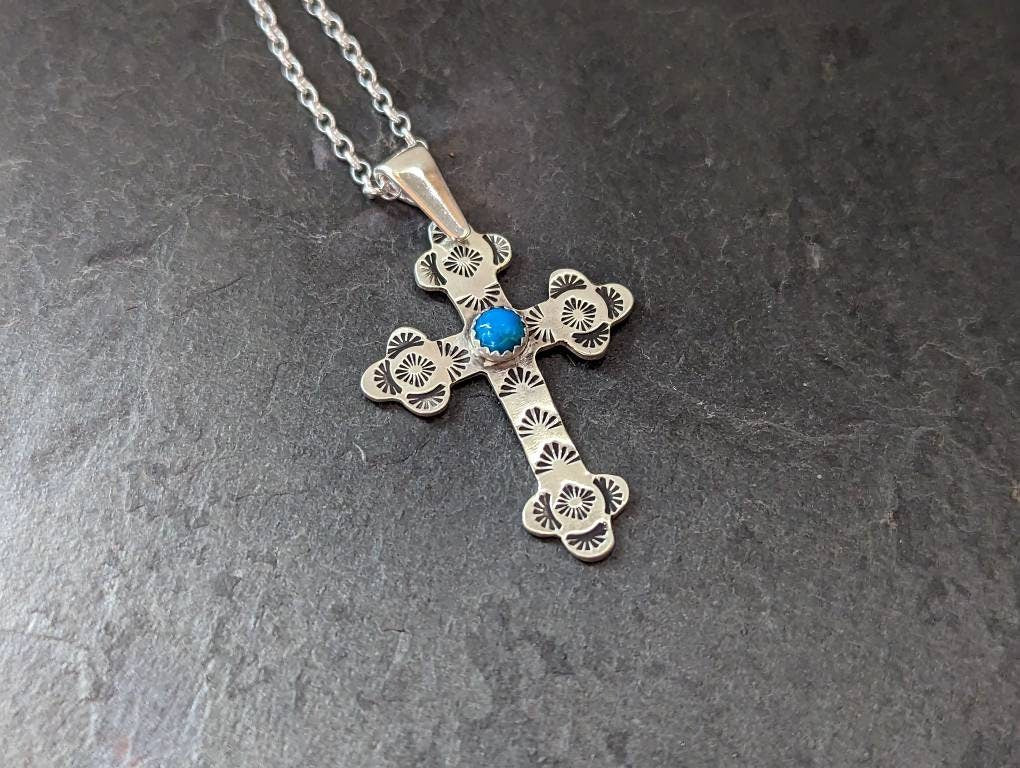 Sterling silver cross with a hand stamped pattern and a 5 mm Kingman turquoise