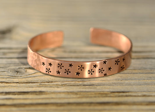 Copper cuff bracelet with small flowers and a hammered texture