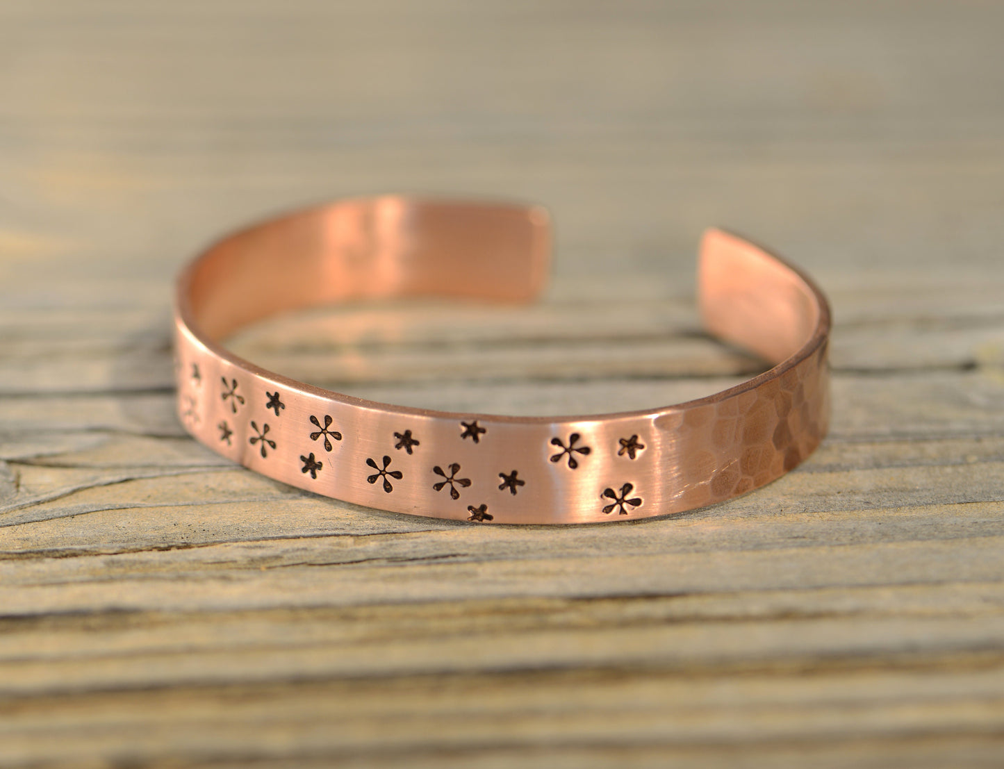 Copper cuff bracelet with small flowers and a hammered texture