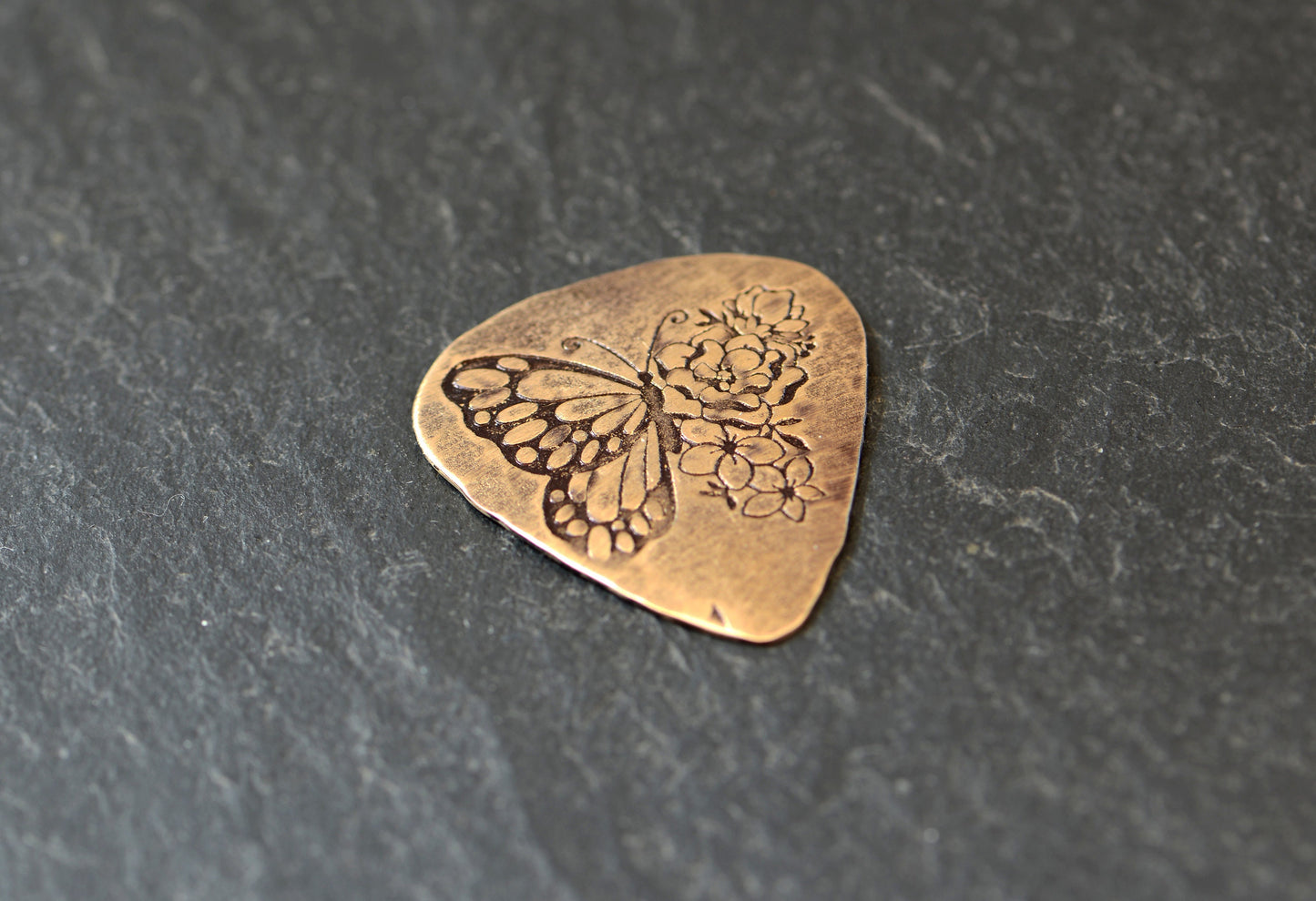 Bronze guitar pick with butterfly and flowers