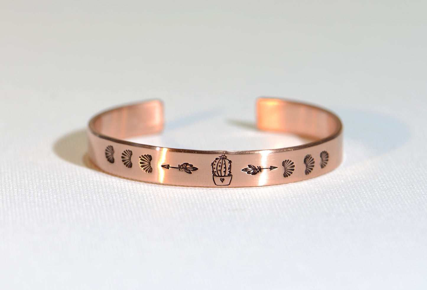 Guitar pick copper bracelet with cactus in a pot along with arrows