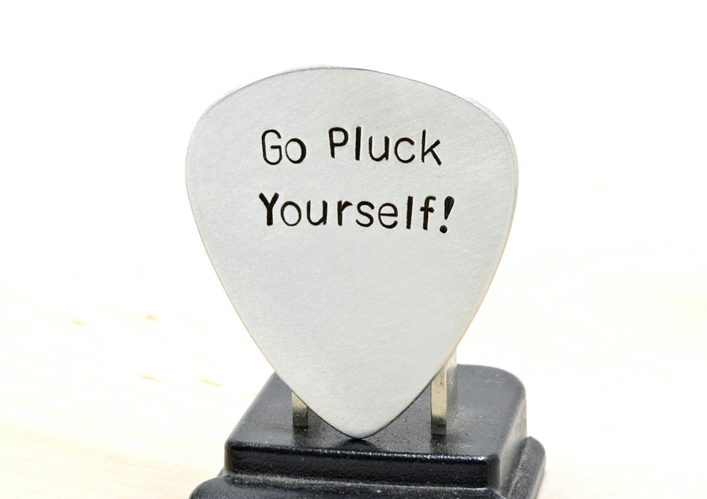 Silver guitar pick with Go Pluck Yourself
